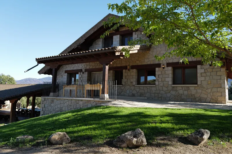La casa de piedra y madera rodeada de césped