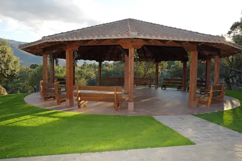 Cenador de madera en el jardín, con la sierra al fondo