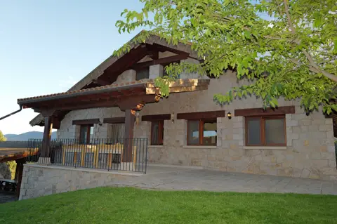 La casa y su balcón, a la sombra de los árboles