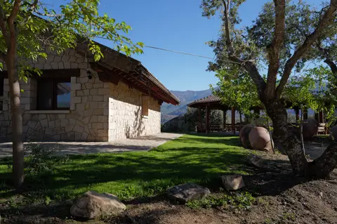 Lateral de la casa entre árboles, con el cenador al fondo