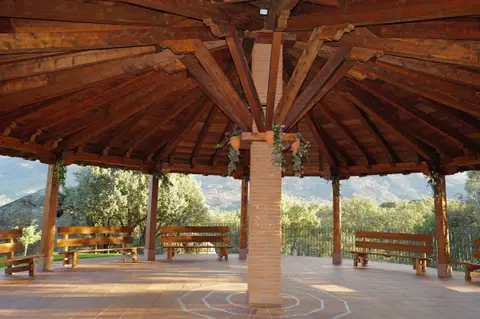 Interior del cenador de madera, con bancos y vistas